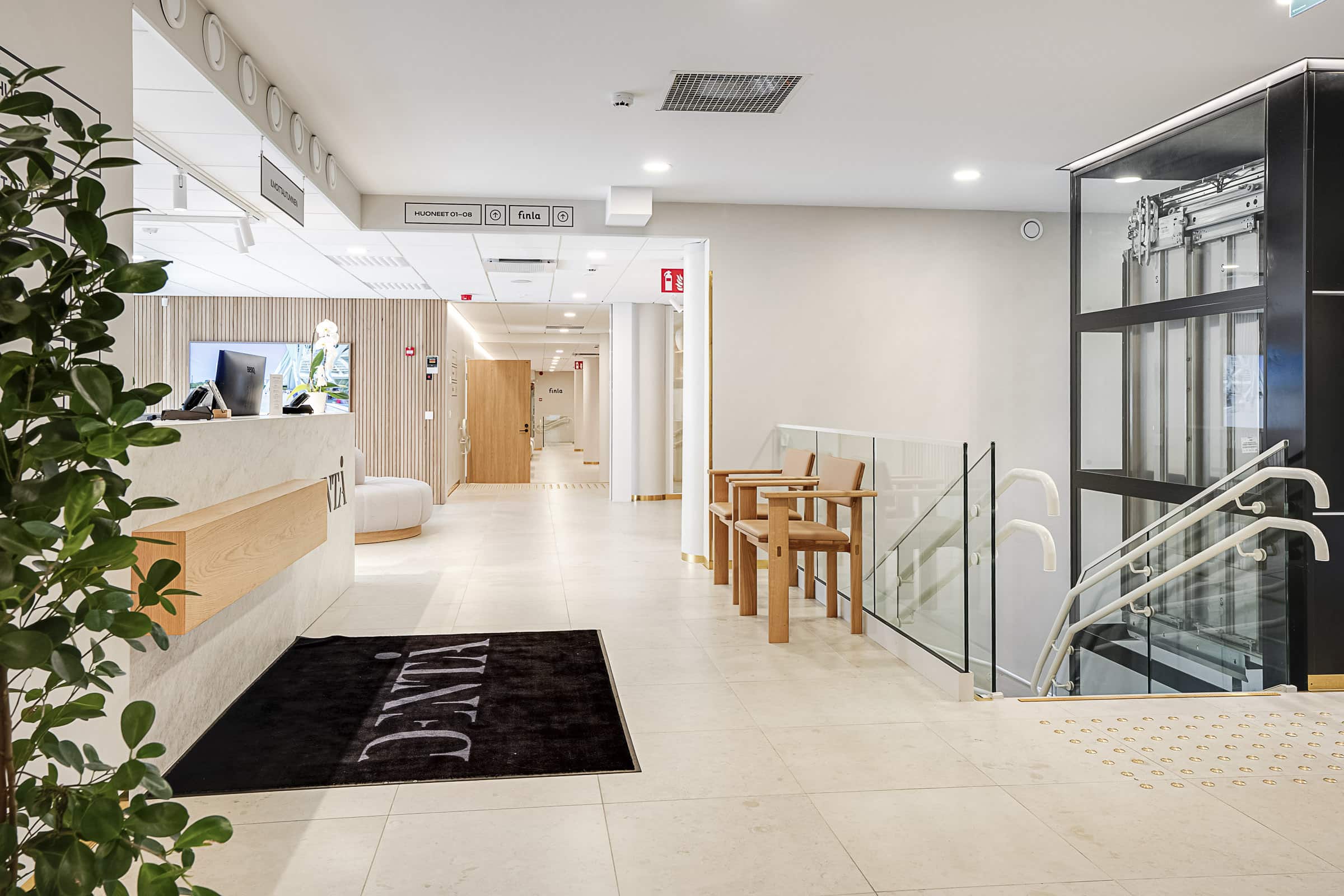 Dentån toimitilat kuvattuna. Vasemmalla asiakspalvelutiski ja oikealla toisen kerroksen vastaanotolle tulevat portaat. Taustalla käytävä, jossa huoneet sijaitsevat. Suuhygienisti Turku.